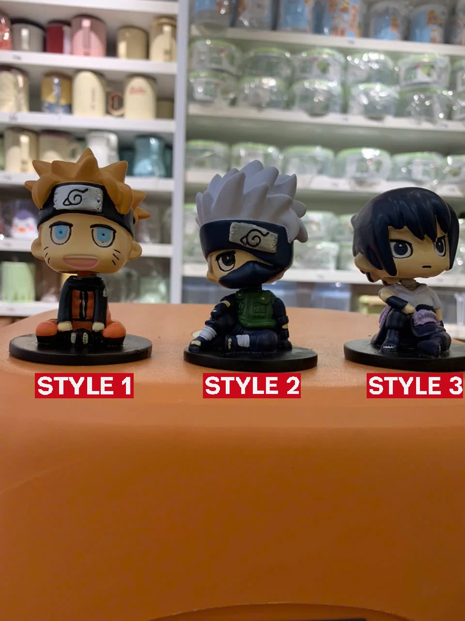 Three Naruto figures placed on a table with store shelves behind!