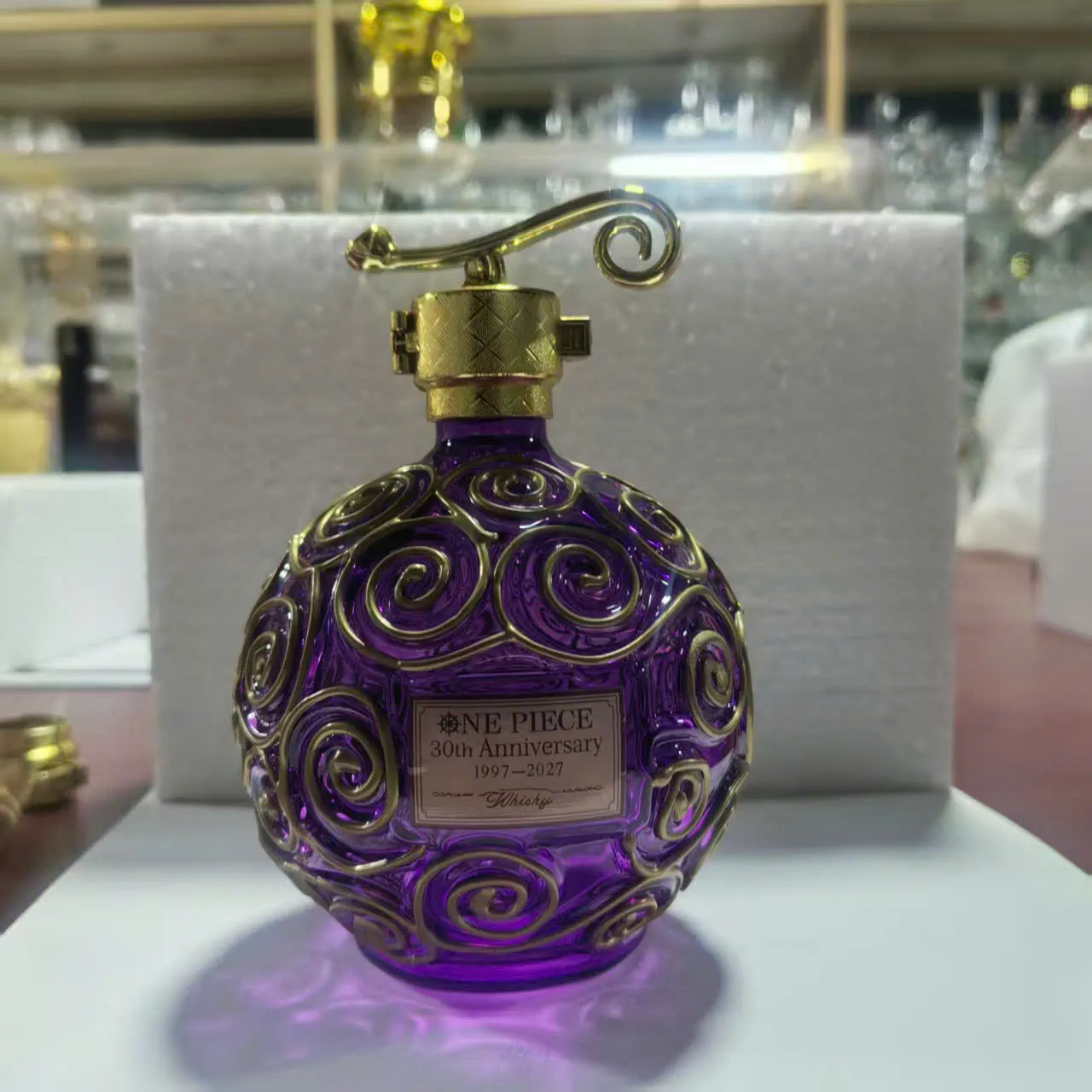 Purple glass bottle with gold swirl design and One Piece anniversary label!