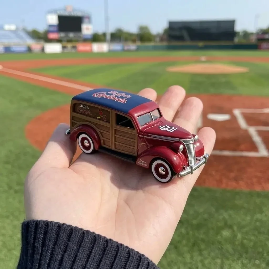 Hot Wheels St. Louis Cardinals 1937 Woody Wagon Vintage Car Model 3 Hand holding Hot Wheels St. Louis Cardinals 1937 Woody Wagon toy above a baseball field.
